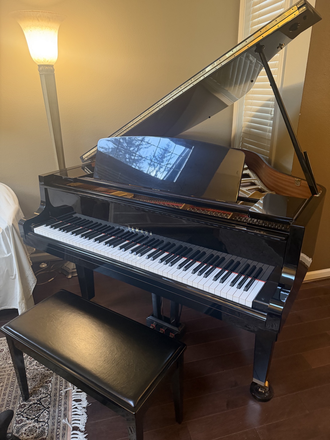 A polished black Yamaha grand piano with its lid raised in a home